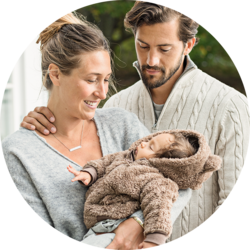 Smiling parents looking lovingly at their newborn baby wrapped in a brown blanket